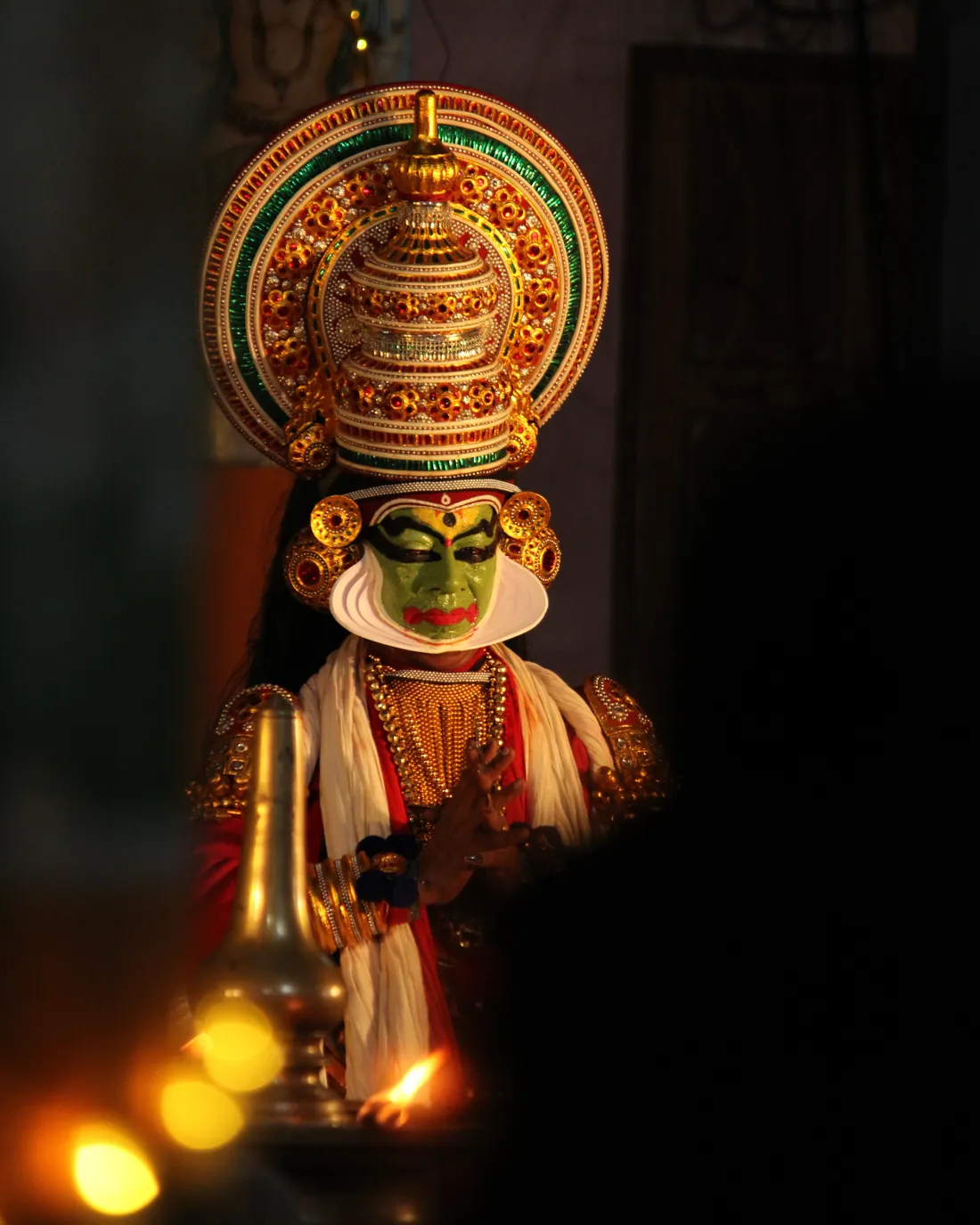 Close-up of a Kathakali performer's elaborate green and red painted face and eyes